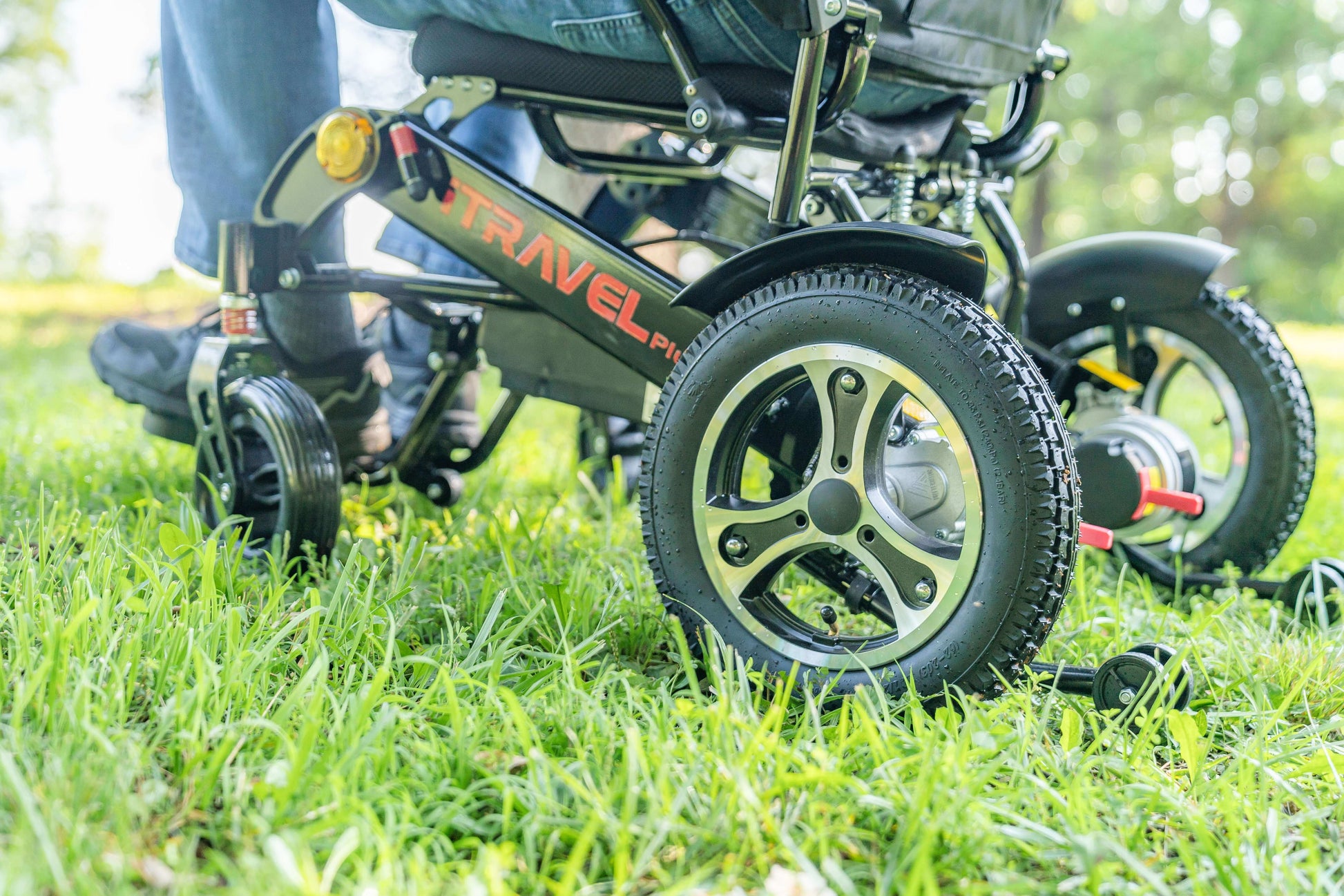 Metro Mobility iTravel Plus Electric Wheelchair - rear left side angle close up wheel lifestyle view with model